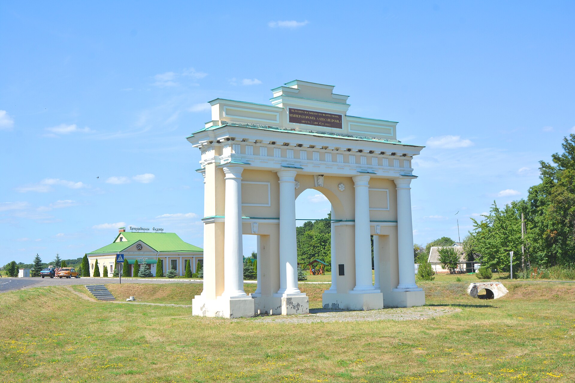 Тріумфальна арка в Диканьці: великий центральний проїзд, два нижчі проходи, білі колони та ступінчасте завершення