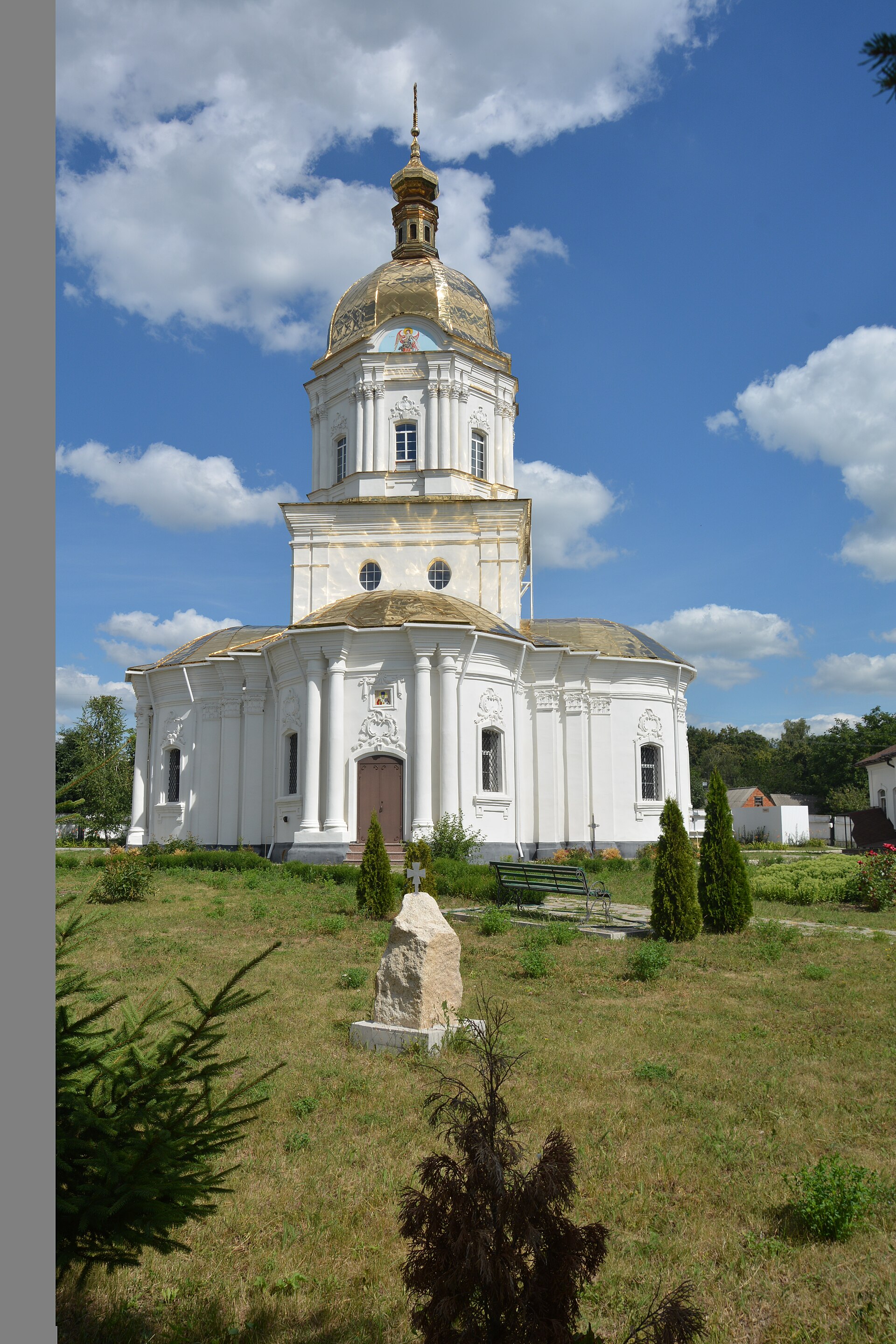 Троїцька церква в Диканьці: білий оздоблений фасад, округлі бічні частини та високий золотавий купол