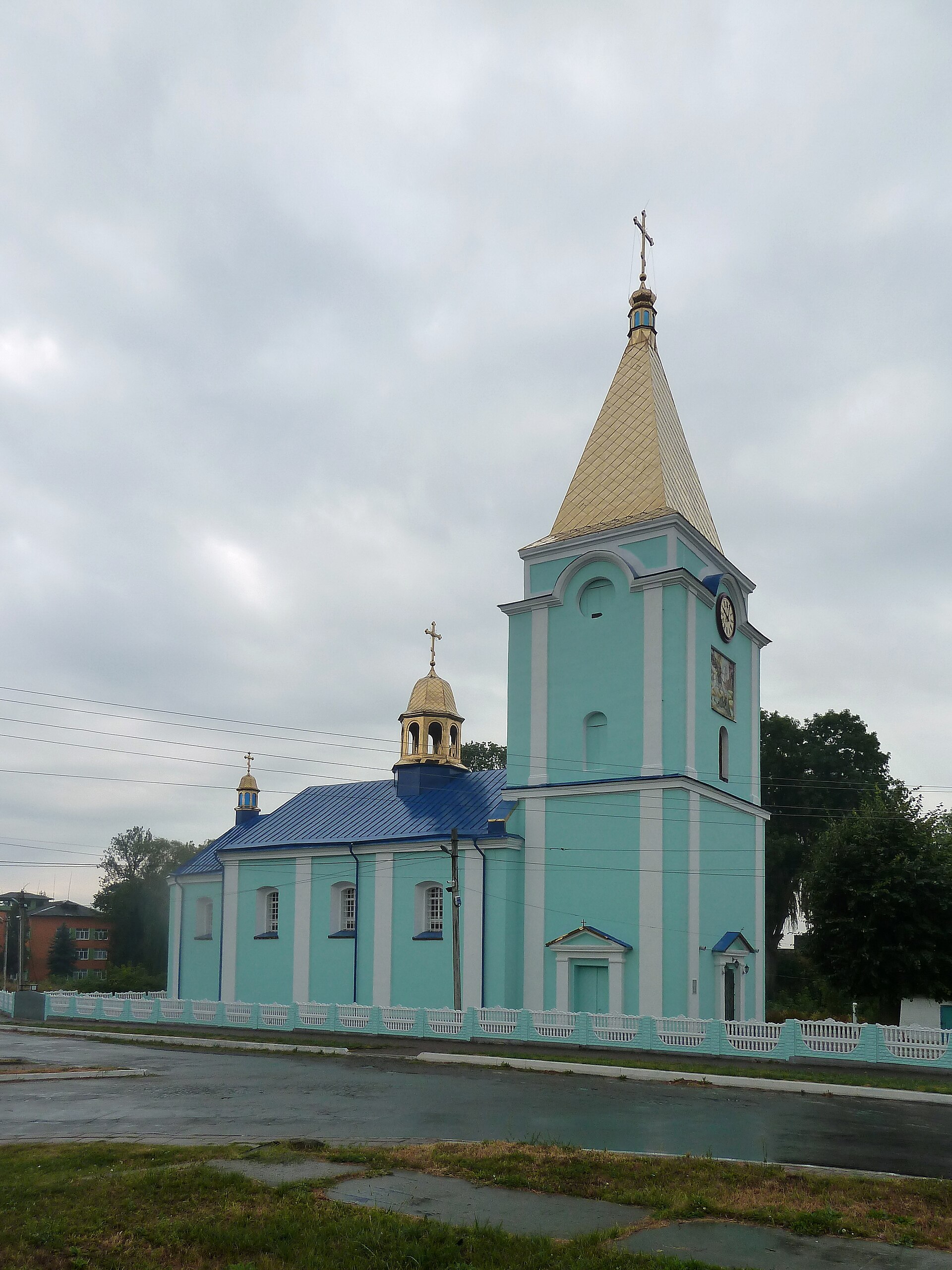 Георгіївська церква в Любомлі: видовжений світло-зелений храм із синім дахом і приєднаною високою дзвіницею