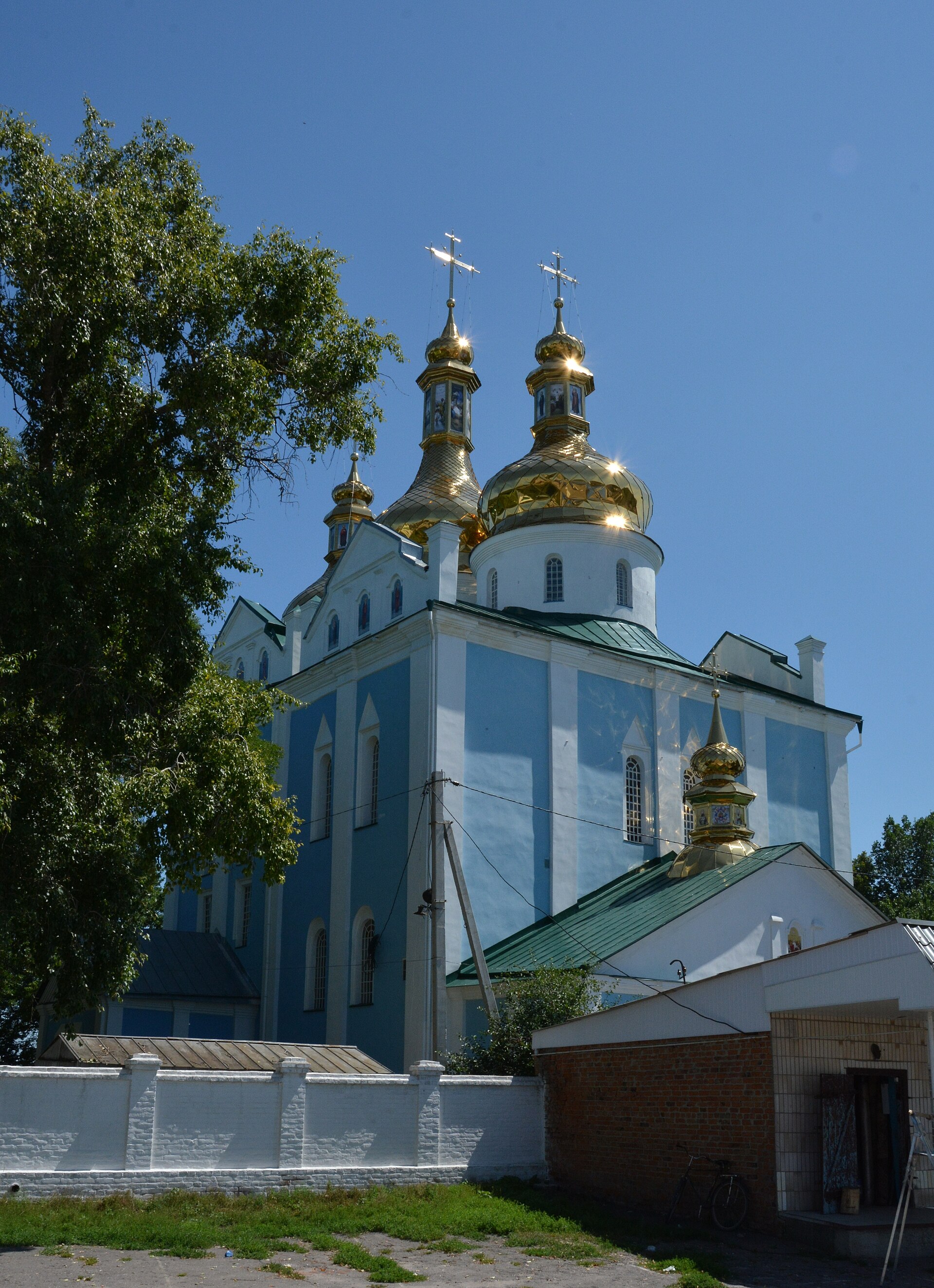 Святодухівський собор у Ромнах: три позолочені бані над світлими стінами та нижчі прибудови