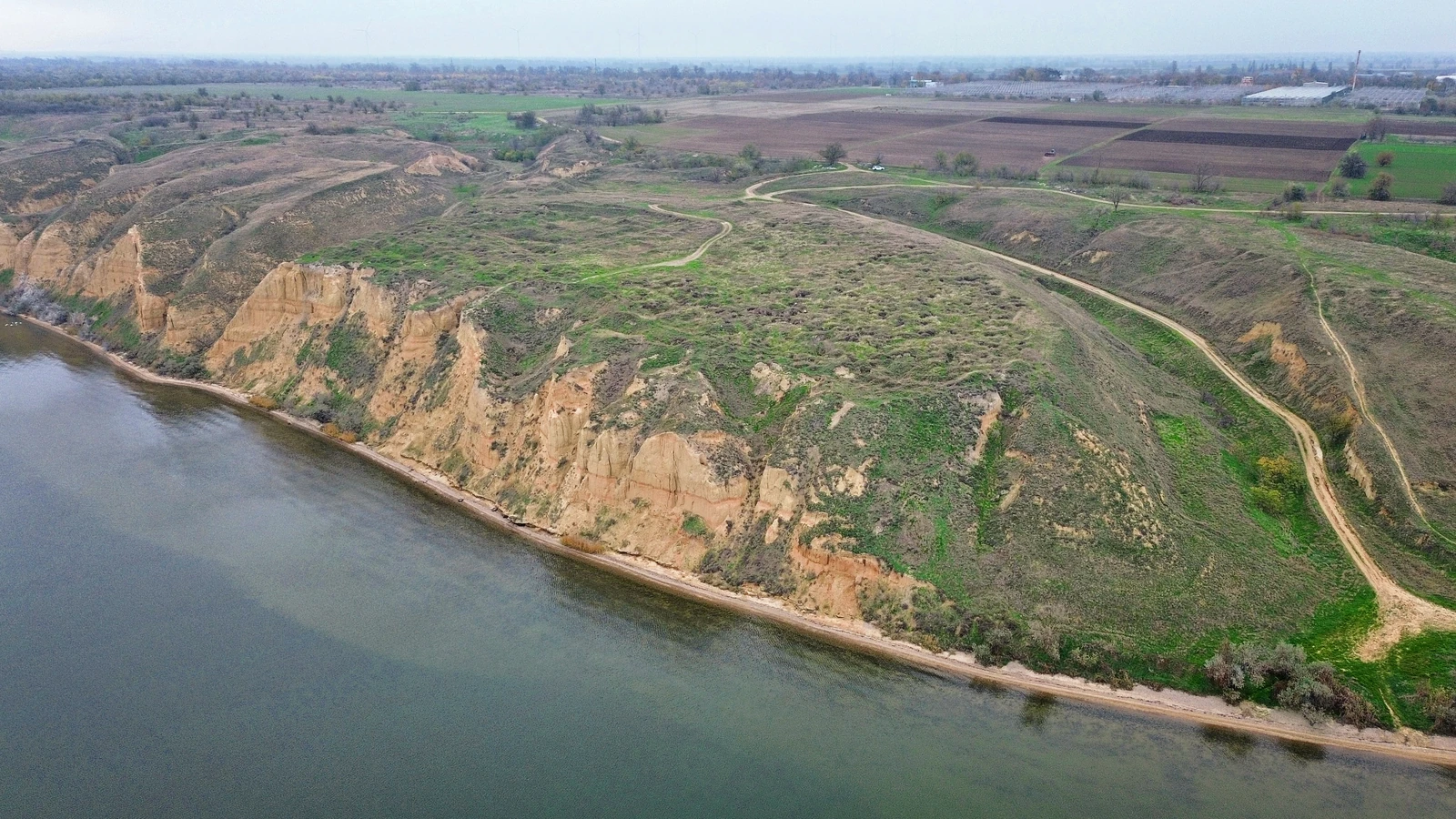 Заросла травою площадка над високими світлими урвищами на березі лиману; угорі видно стежки, балки й поля.